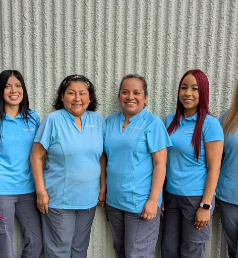 eight ladies wearing merry maids uniforms smiling for a photo